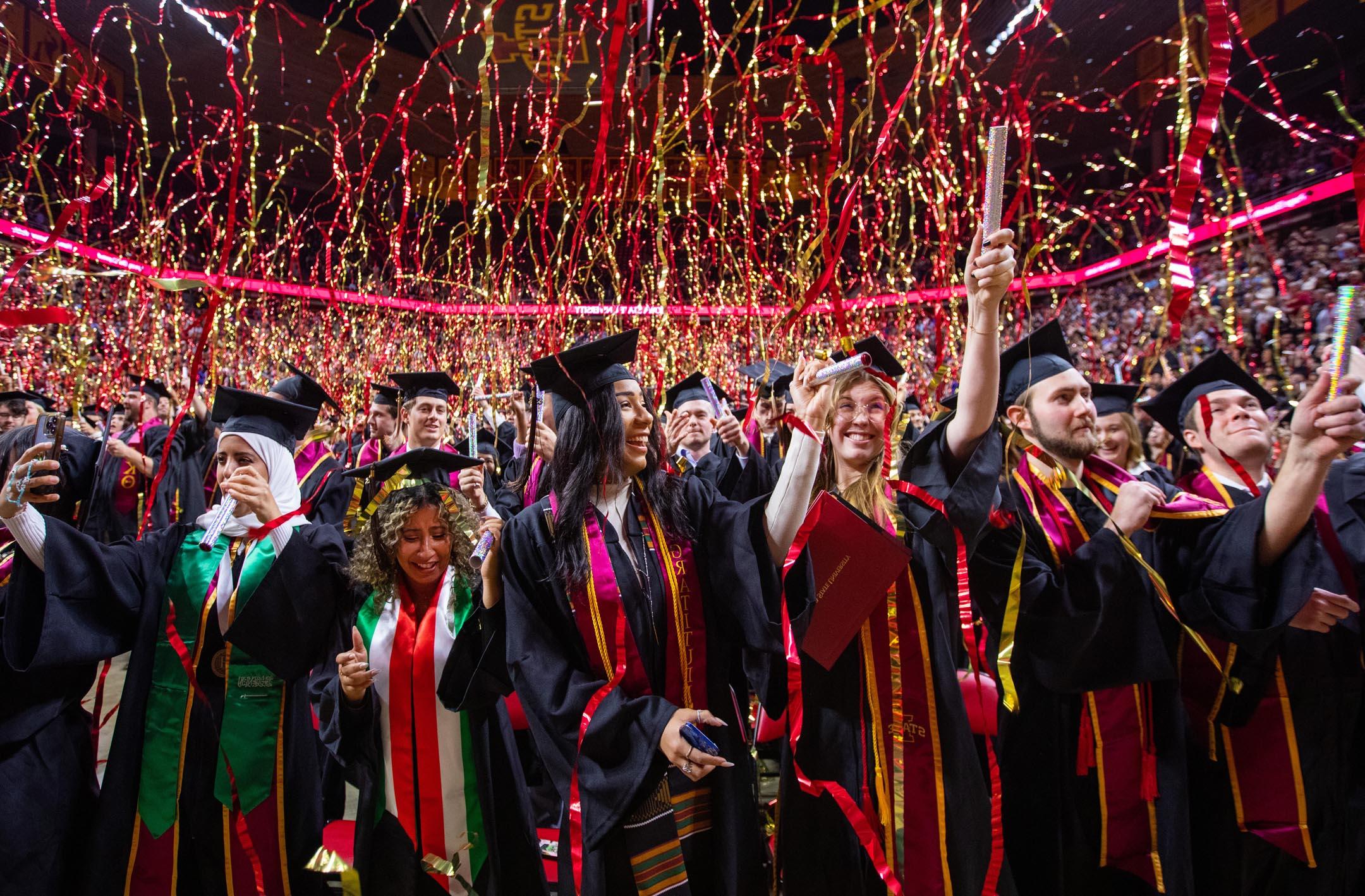 毕业生们在毕业典礼结束时庆祝，彩带从上方落下.